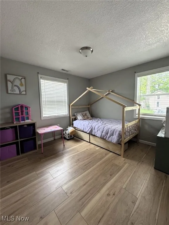 Bedroom with wood-type flooring, a textured ceiling, and baseboards