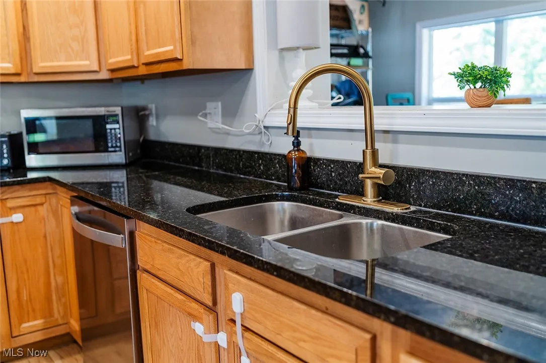 Kitchen featuring stainless steel appliances, dark stone counters, and brown cabinets