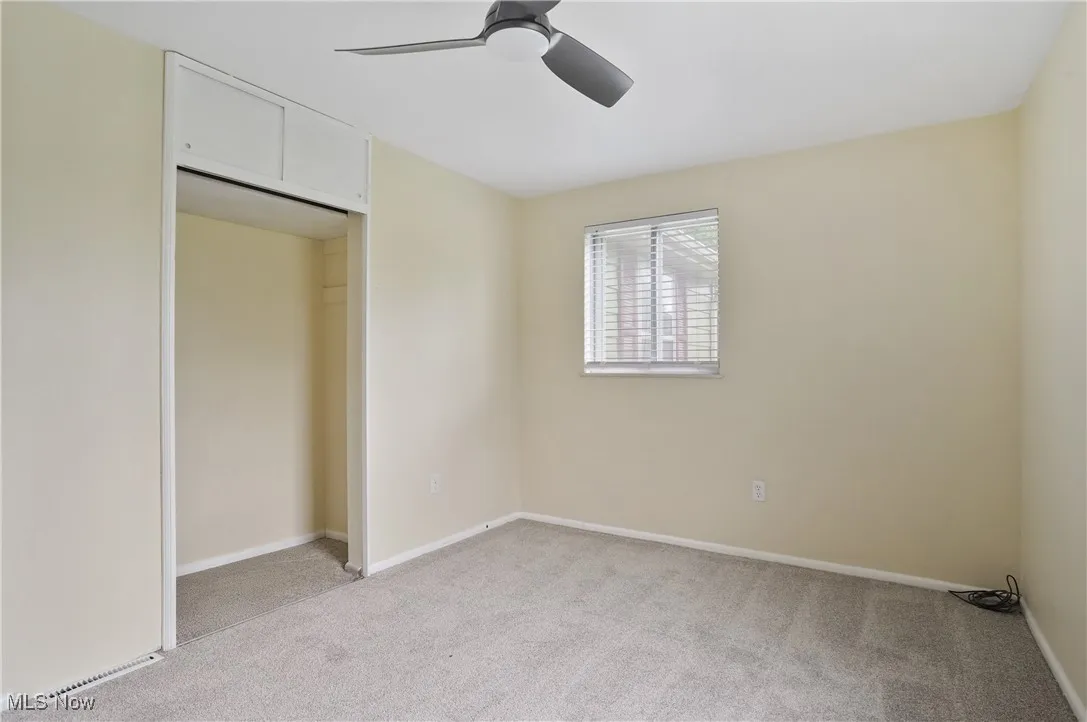 Unfurnished bedroom featuring light colored carpet, baseboards, a closet, and ceiling fan