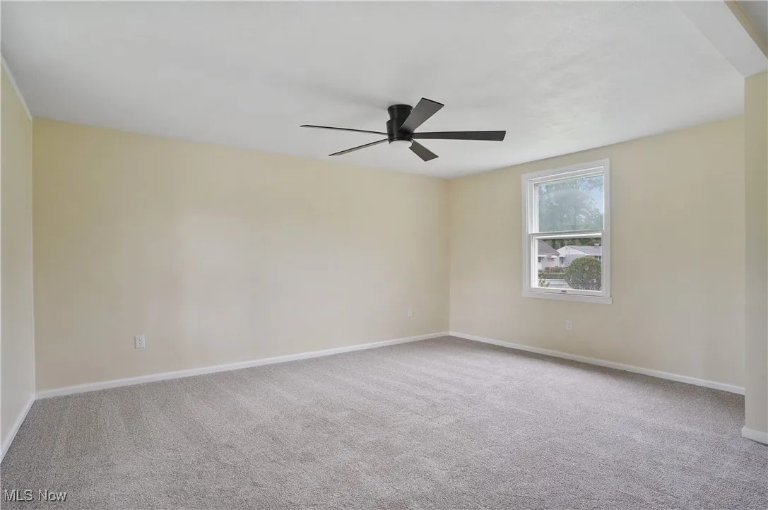 Spare room featuring ceiling fan, carpet floors, and baseboards