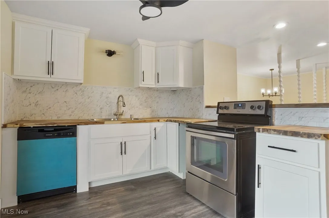 Kitchen with dishwasher, stainless steel range with electric cooktop, wood counters, a sink, and dark wood finished floors