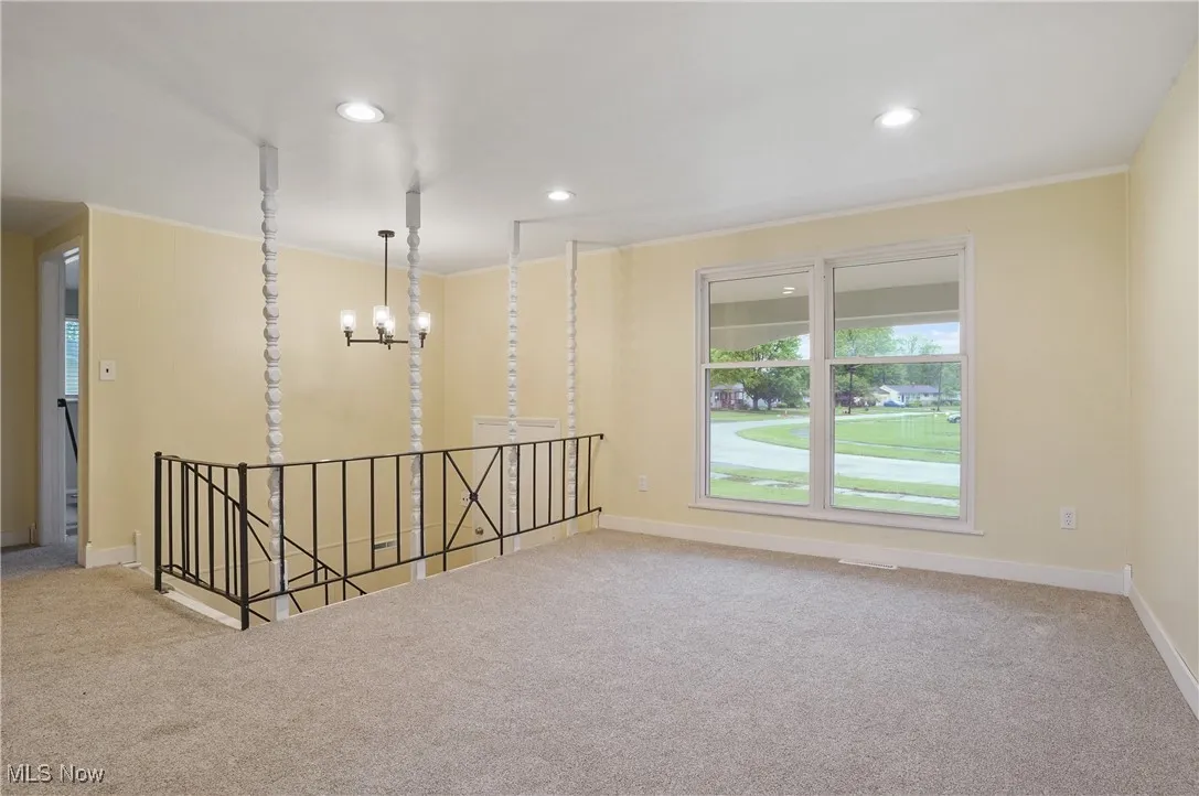Carpeted spare room with ornamental molding, baseboards, recessed lighting, and a chandelier