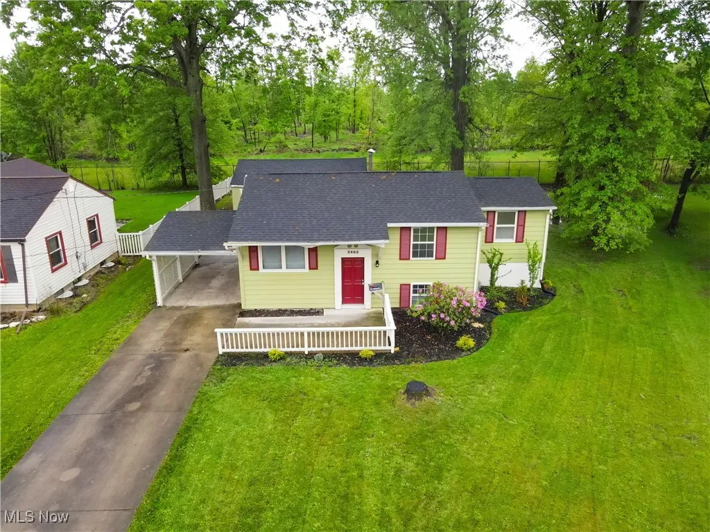 View of front of property featuring driveway, roof with shingles, and a carport