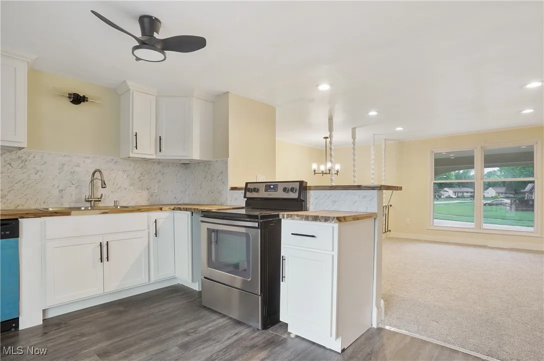 Kitchen featuring stainless steel electric range, wooden counters, a peninsula, a sink, and recessed lighting