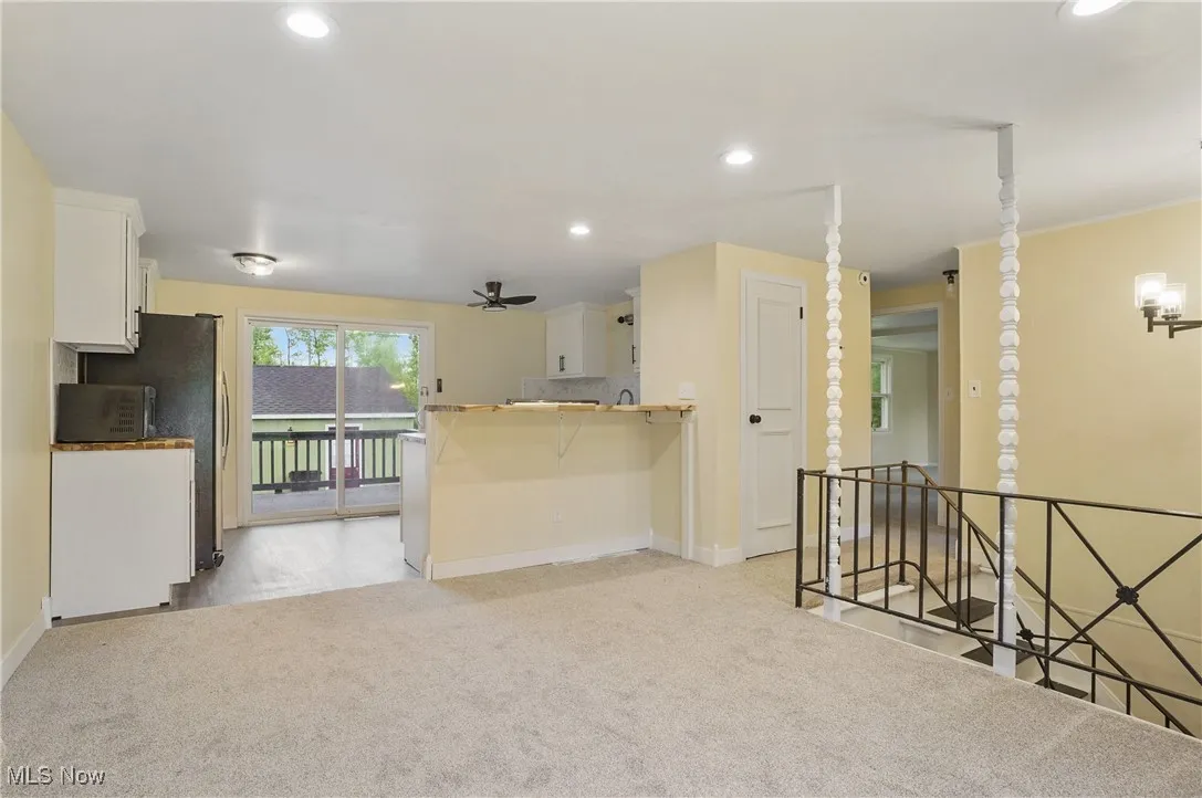 Kitchen with baseboards, light carpet, white cabinets, recessed lighting, and a peninsula