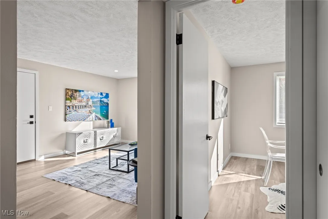 Corridor with a textured ceiling, wood finished floors, and baseboards