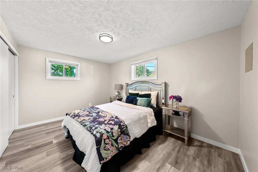 Bedroom featuring wood finished floors, a closet, multiple windows, baseboards, and a textured ceiling