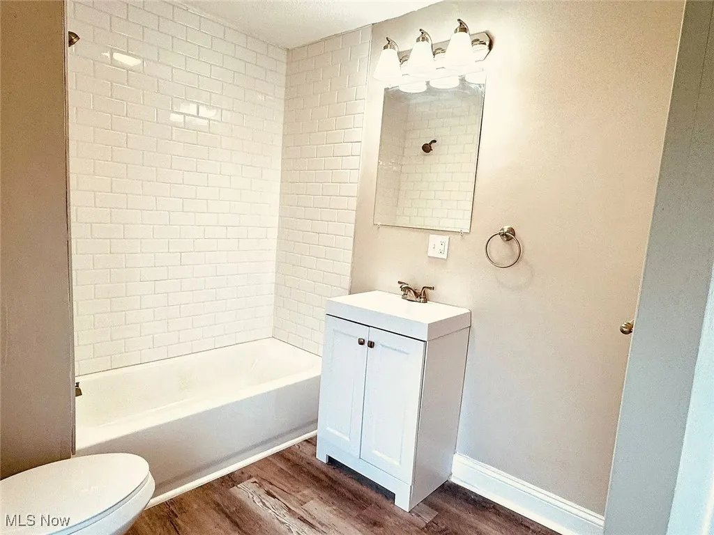 Full bath featuring wood finished floors, toilet, vanity, and shower / bath combination