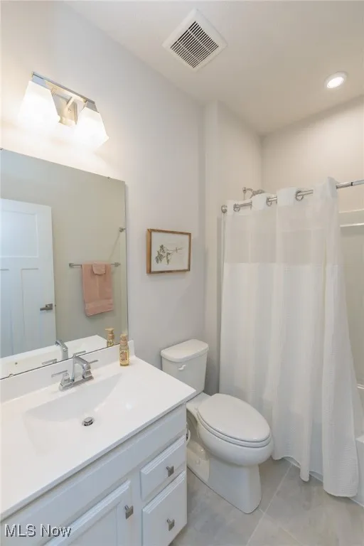 Full bath with vanity, commode, shower / bath combination with curtain, and tile patterned floors