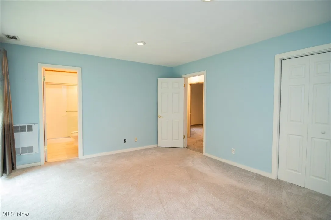 Unfurnished bedroom with light carpet, baseboards, a closet, recessed lighting, and ensuite bathroom