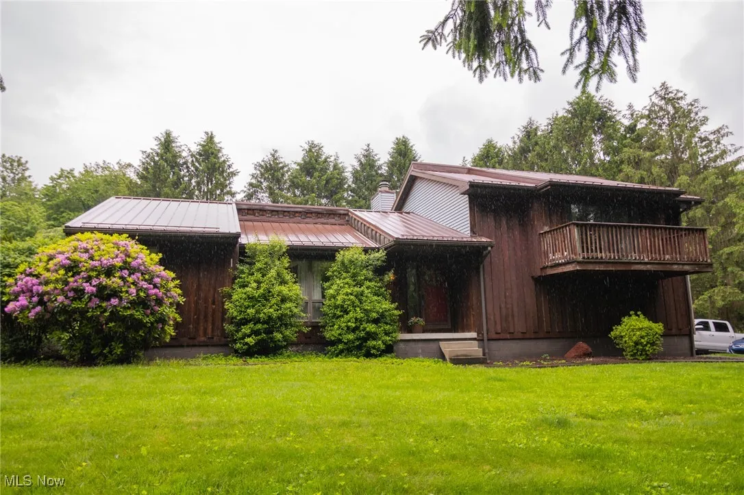 View of front of house featuring a front yard, a chimney, metal roof, and a standing seam roof