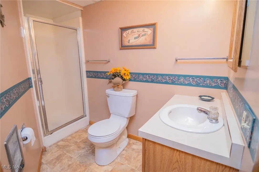 Bathroom featuring toilet, a shower stall, and vanity