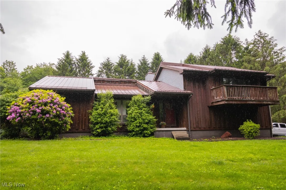 View of front of house with a front lawn, a chimney, metal roof, and a standing seam roof