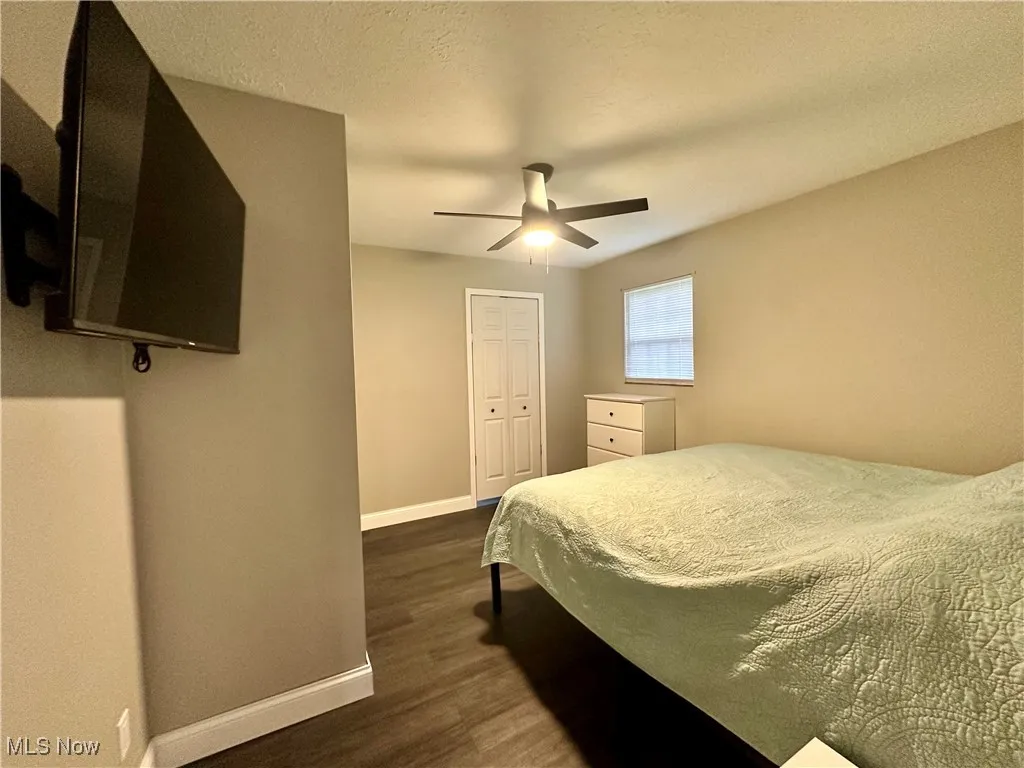 Bedroom featuring baseboards, dark wood-type flooring, ceiling fan, and a closet