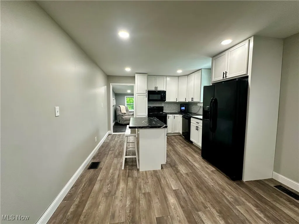 Kitchen featuring black appliances, white cabinetry, dark wood-style floors, dark countertops, and recessed lighting