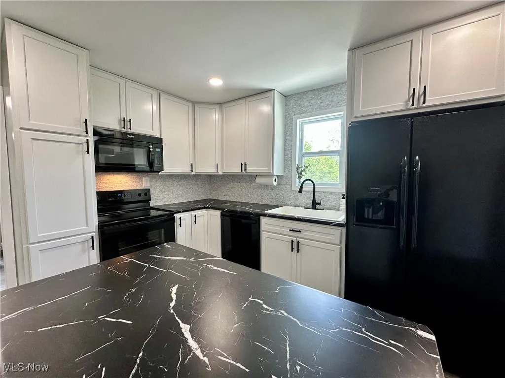 Kitchen featuring black appliances, white cabinets, tasteful backsplash, and recessed lighting