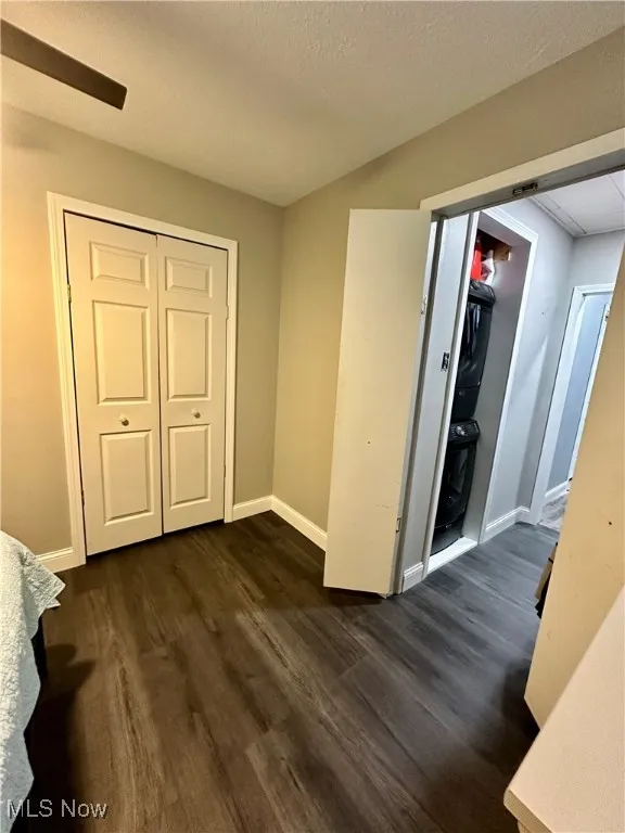 Unfurnished bedroom with dark wood-type flooring, a closet, and baseboards