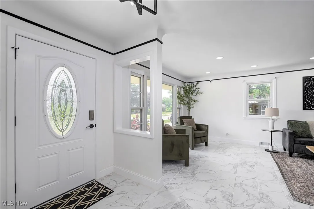 Foyer entrance featuring marble look tiles and recessed lighting