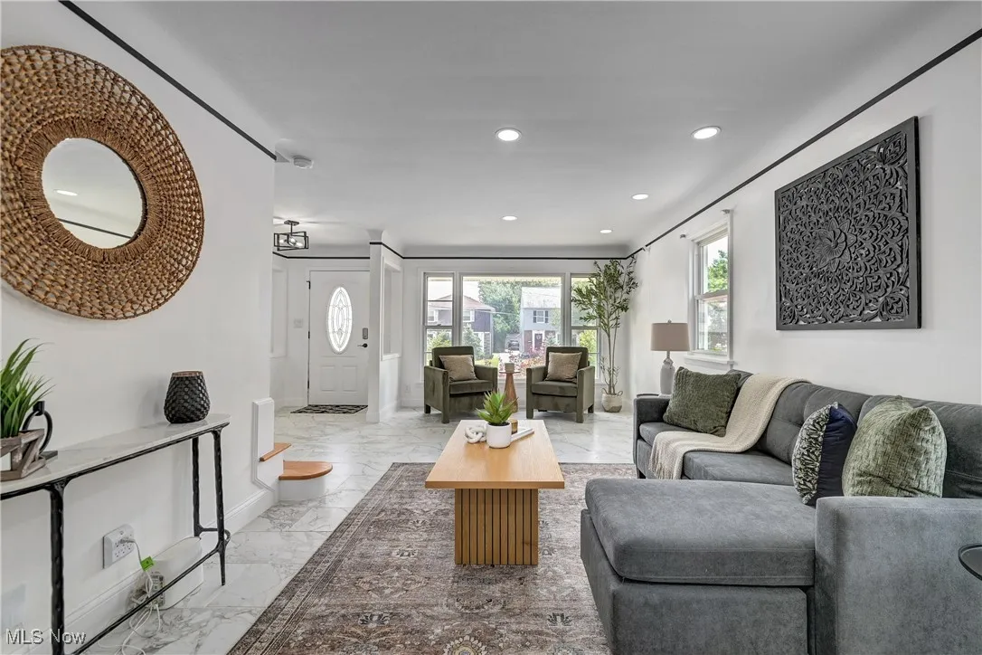 Living area featuring light marble finish floors and recessed lighting.
