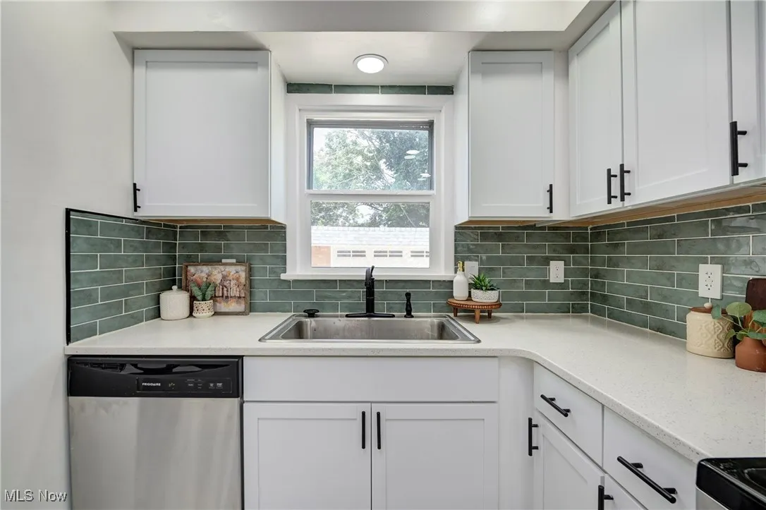 Kitchen with dishwasher, white cabinets, light countertops, and tasteful backsplash