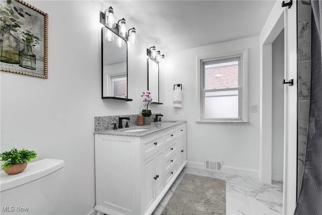 Full bathroom with marble look tile flooring and double vanity