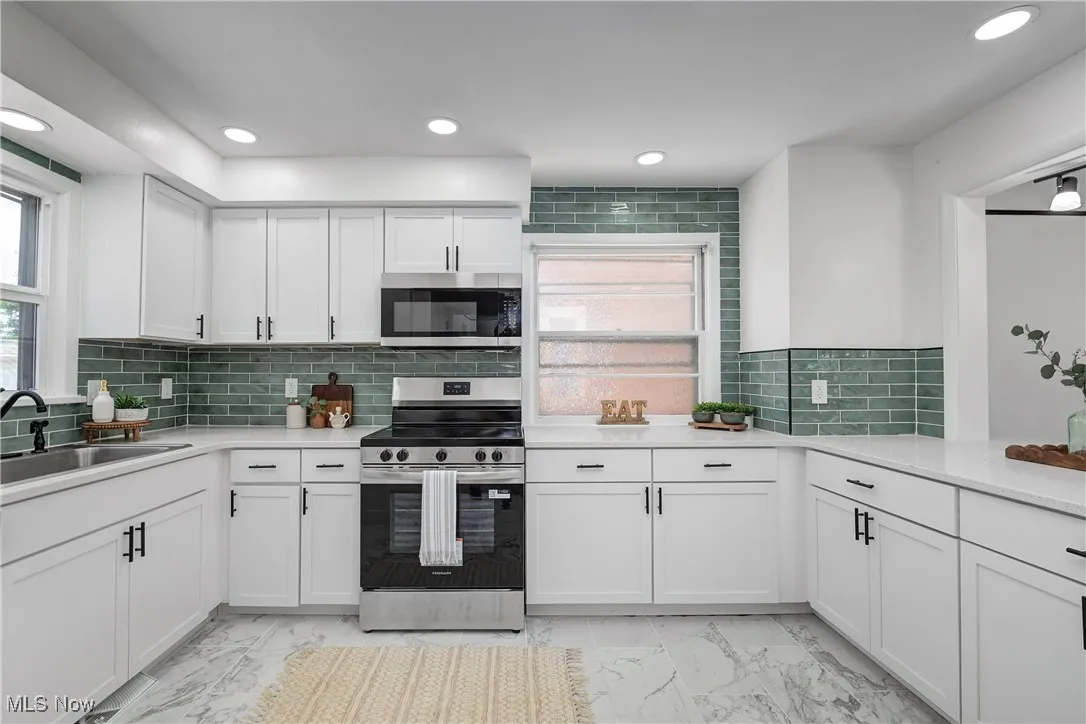Kitchen with appliances with stainless steel finishes, light marble finish floors, light countertops, and recessed lighting.