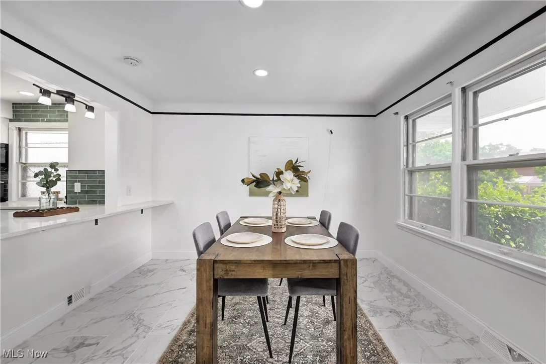 Dining room with marble finish floors and recessed lighting