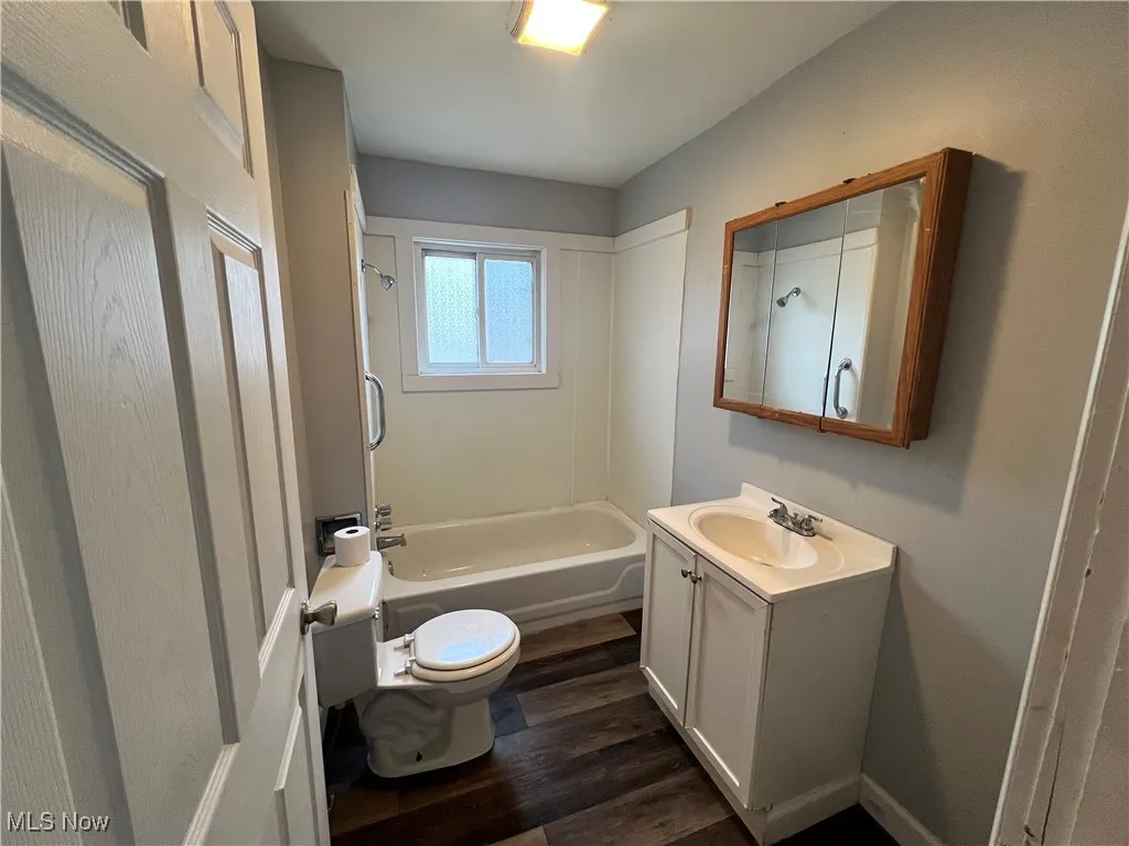 Full bathroom featuring toilet, vanity, wood finished floors, and shower / tub combination