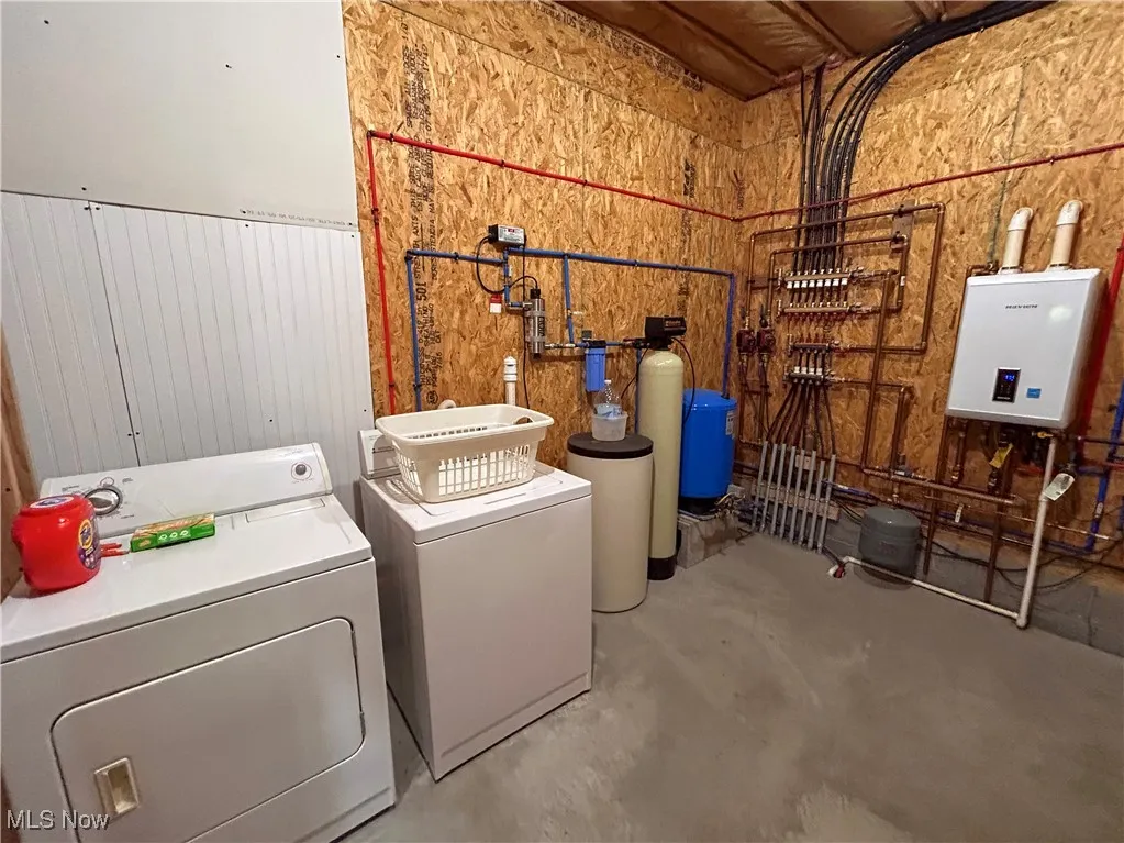 Laundry area featuring washing machine and dryer, water heater, and wooden walls