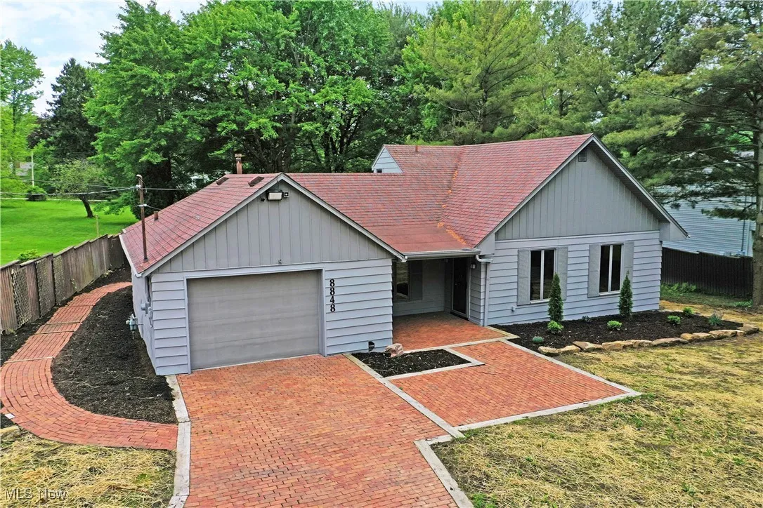 Single story home with a garage, decorative driveway, and board and batten siding