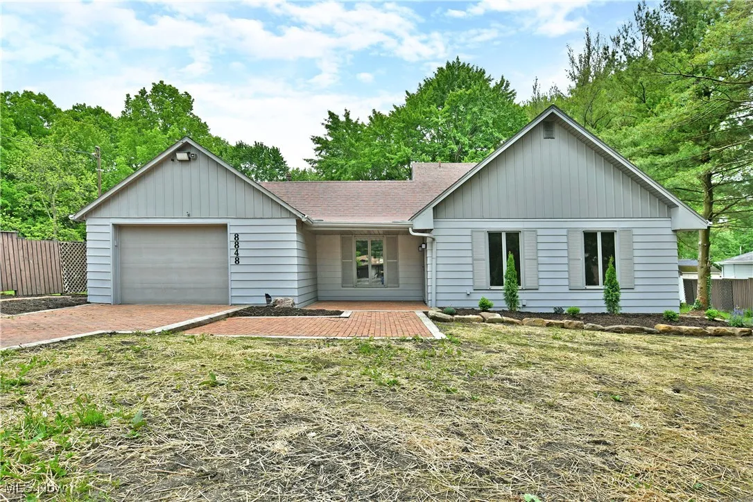 View of front of property with roof with shingles, a garage, and driveway