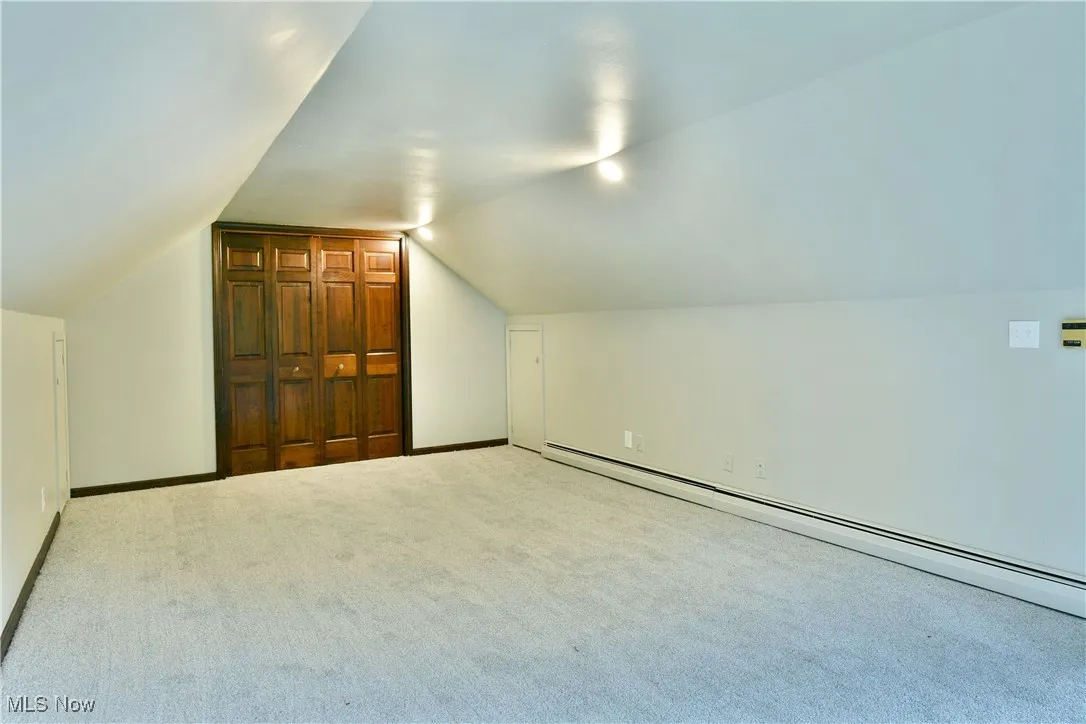 Bonus room with baseboard heating, vaulted ceiling, carpet flooring, and baseboards