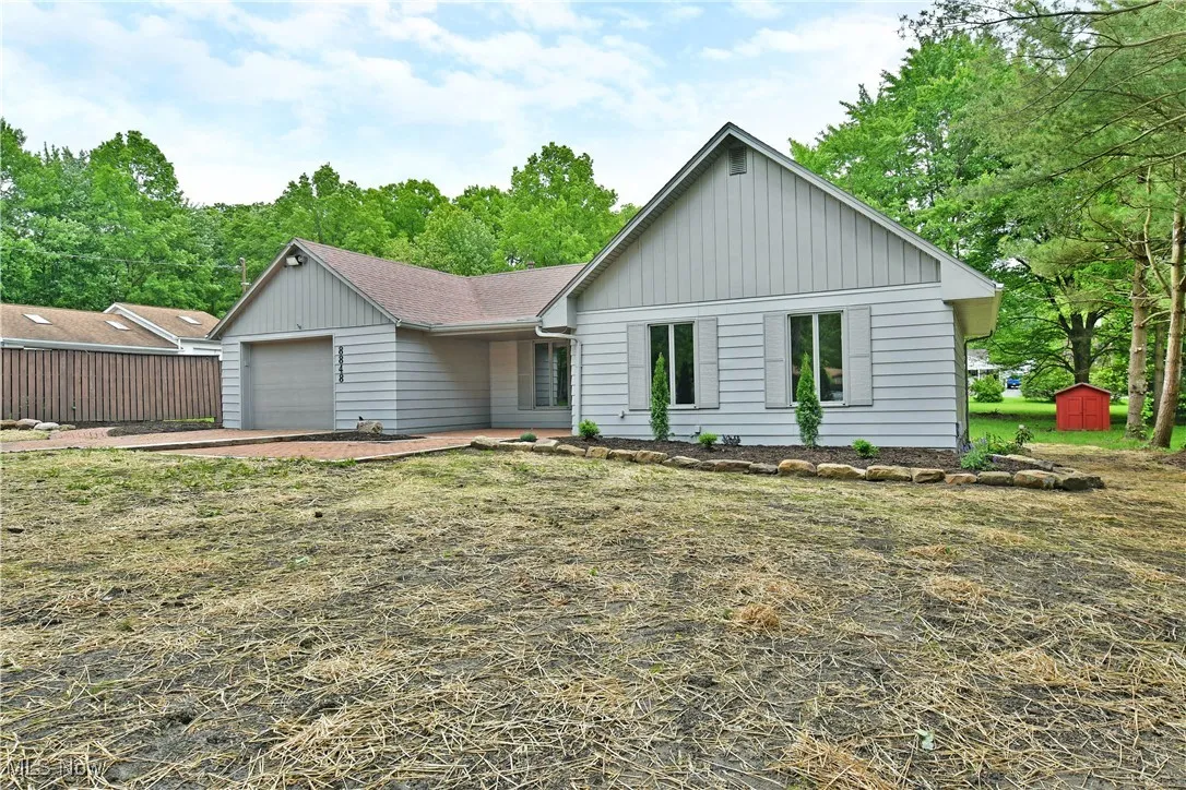 View of front of property with a garage, board and batten siding, a shed, and a shingled roof