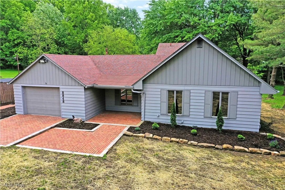 Single story home with a shingled roof, a garage, and board and batten siding