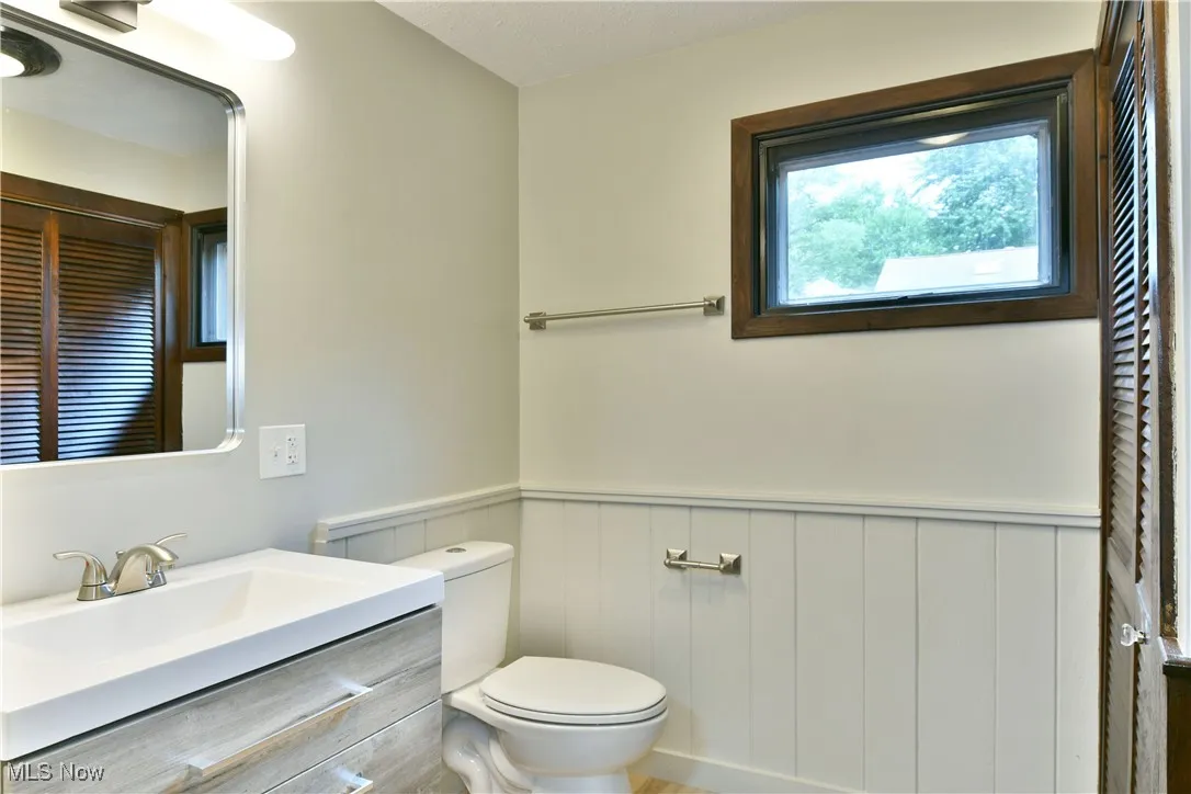 Bathroom with toilet, a wainscoted wall, and vanity