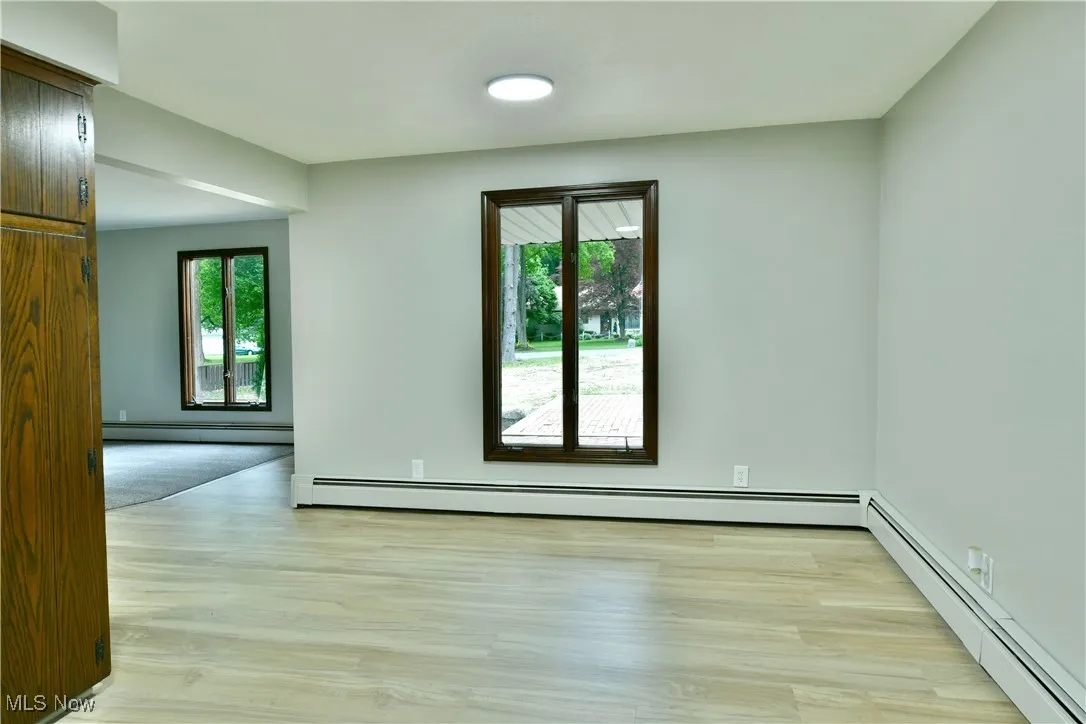 Spare room featuring a baseboard radiator and light wood-style flooring