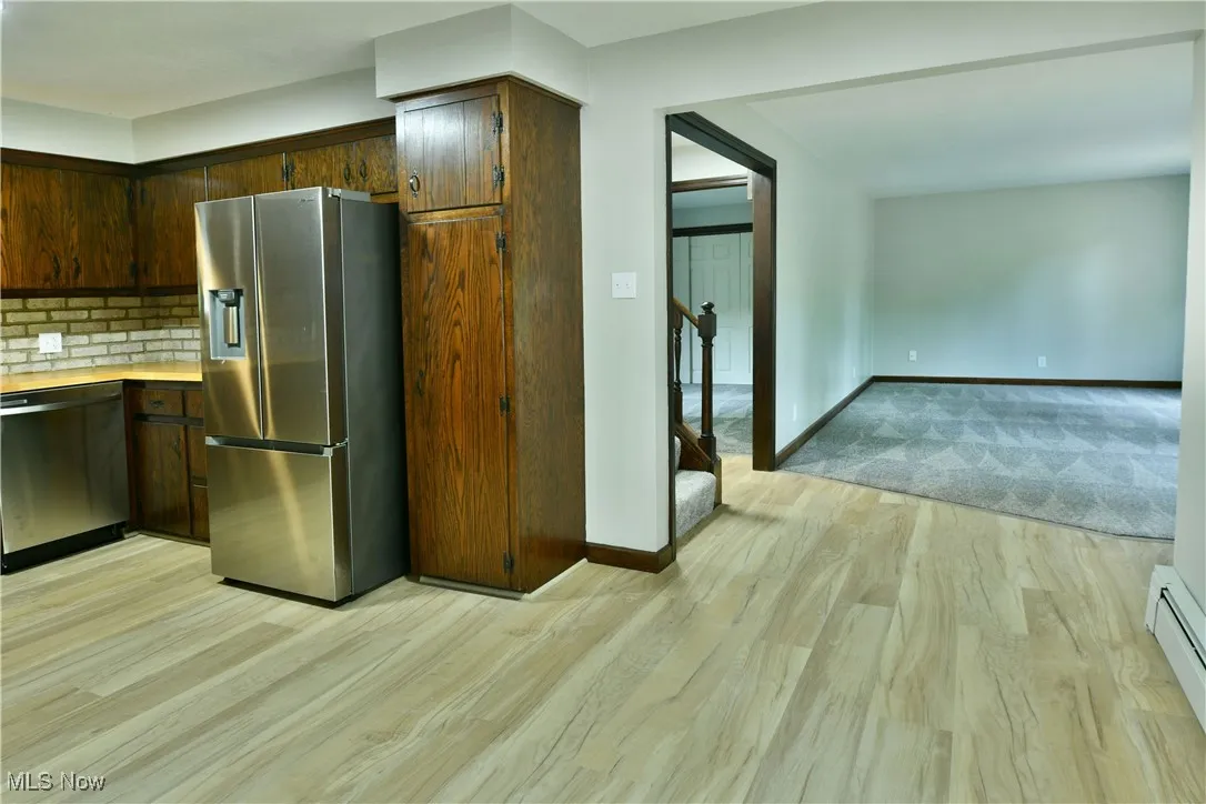Kitchen featuring stainless steel appliances, light wood-style flooring, light countertops, baseboards, and baseboard heating
