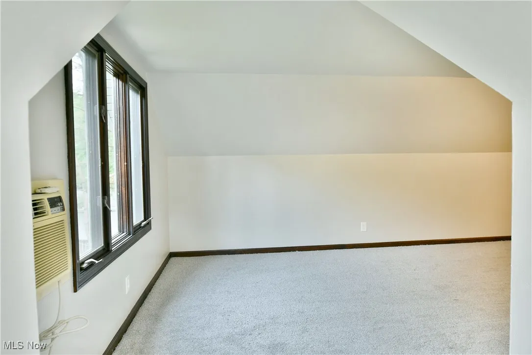 Bonus room with plenty of natural light, carpet flooring, vaulted ceiling, and baseboards