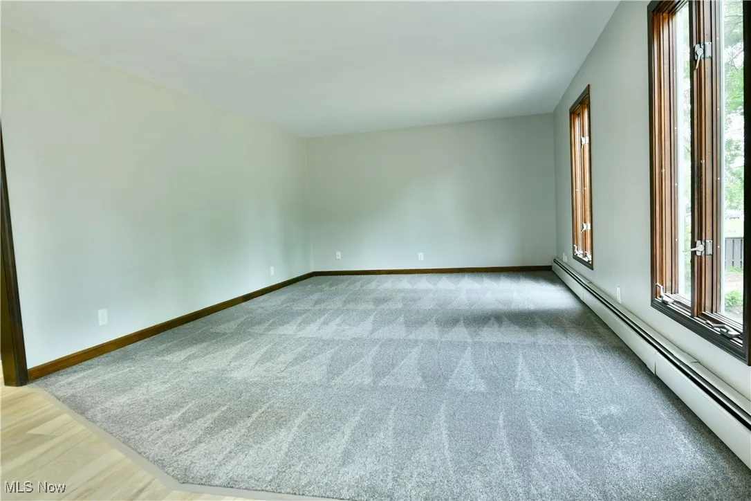 Carpeted empty room with a baseboard radiator and baseboards