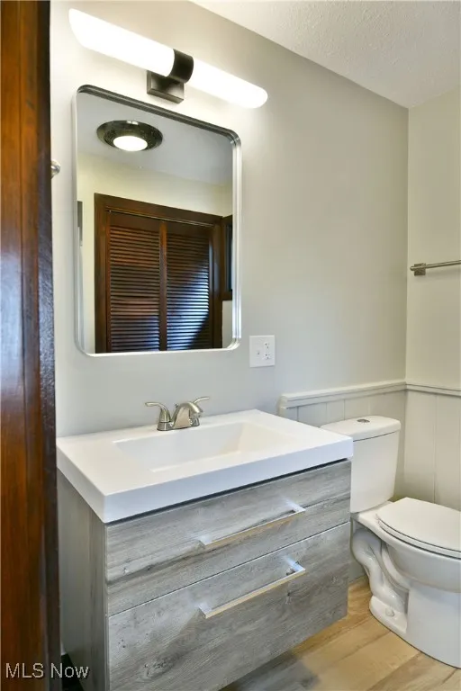 Bathroom featuring vanity, toilet, wood finished floors, and a textured ceiling