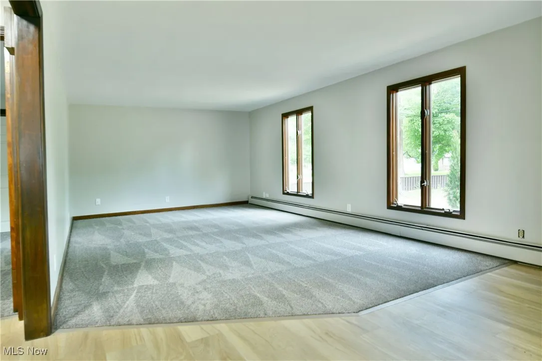 Empty room with baseboard heating, baseboards, and wood finished floors