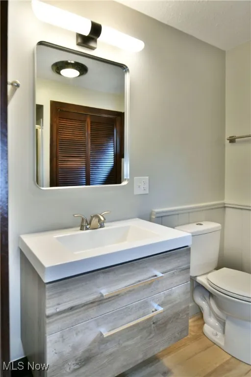 Bathroom with vanity, wood finished floors, toilet, and a textured ceiling