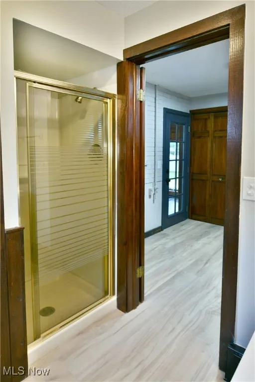 Full bath featuring a shower stall and wood finished floors