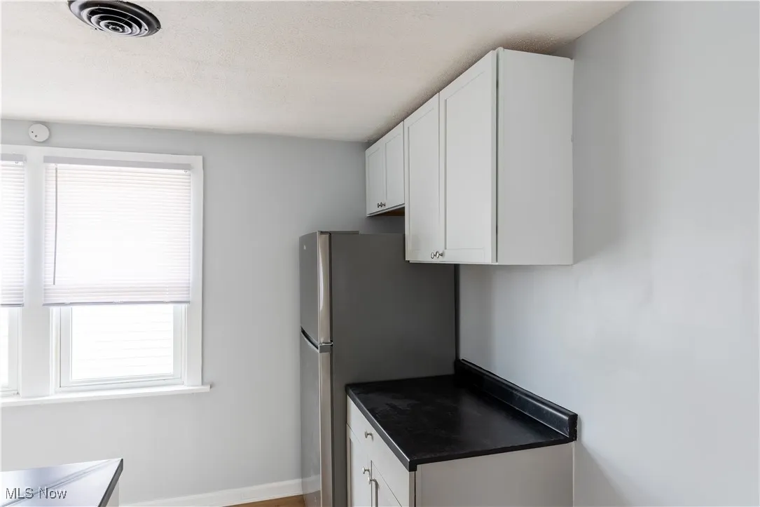 Kitchen featuring white cabinetry and freestanding refrigerator