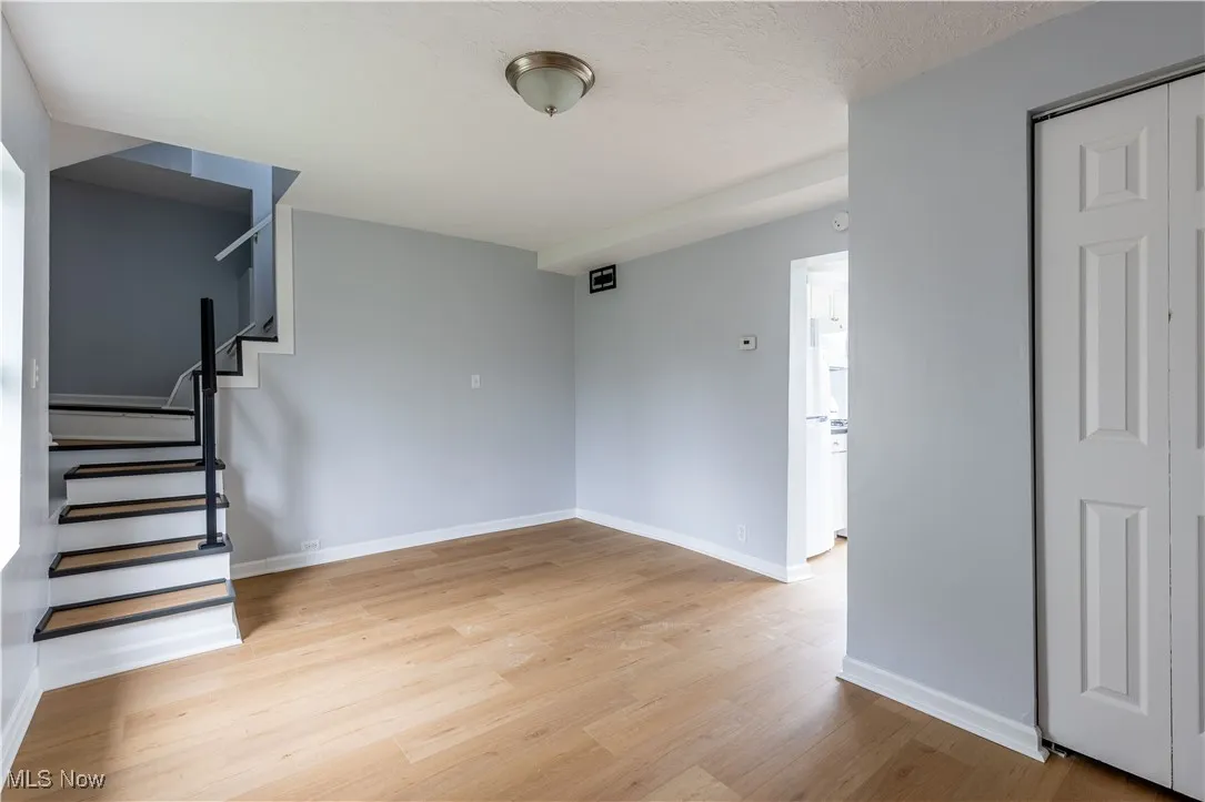 Empty room with light wood-type flooring, baseboards, and stairway