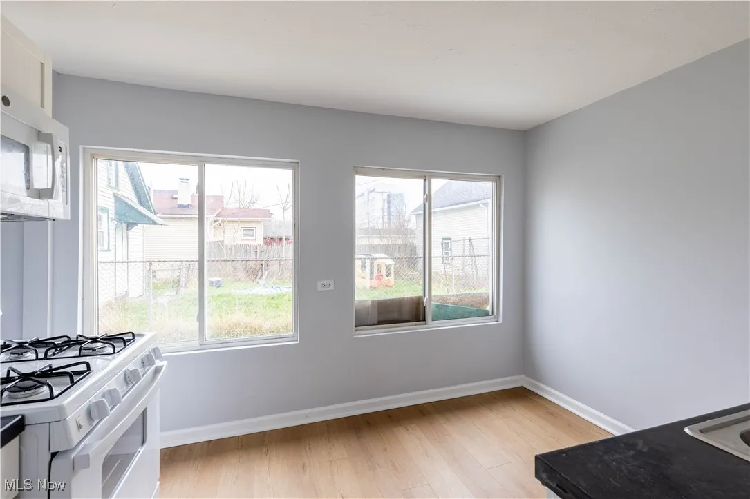 Kitchen with white appliances, light wood finished floors, plenty of natural light, and baseboards