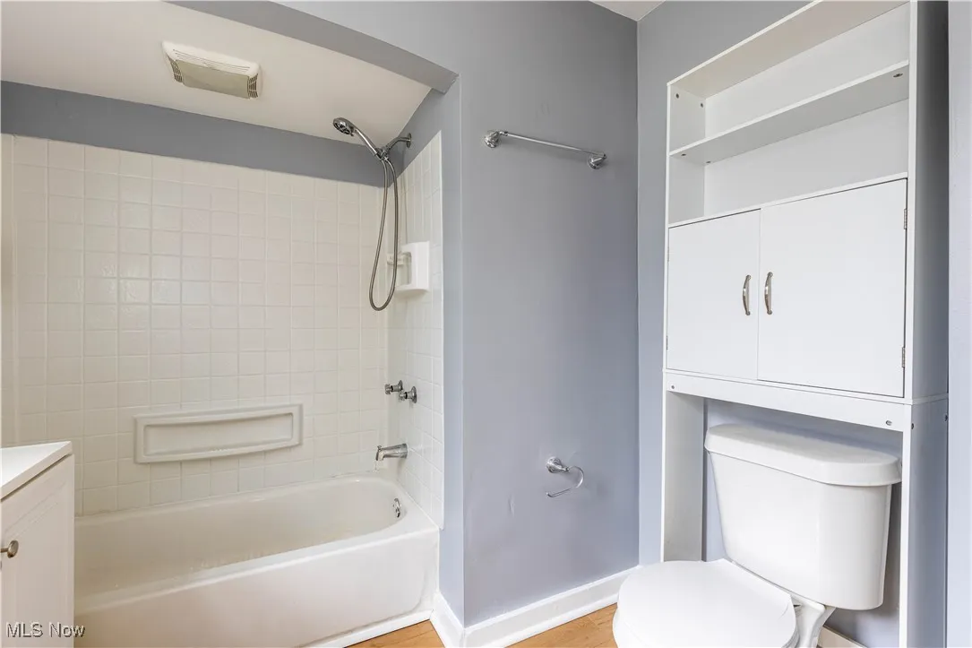 Bathroom with toilet, shower / tub combination, vanity, and baseboards