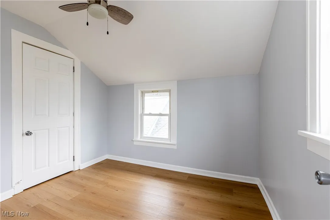 Additional living space with vaulted ceiling, light wood-style floors, baseboards, and ceiling fan