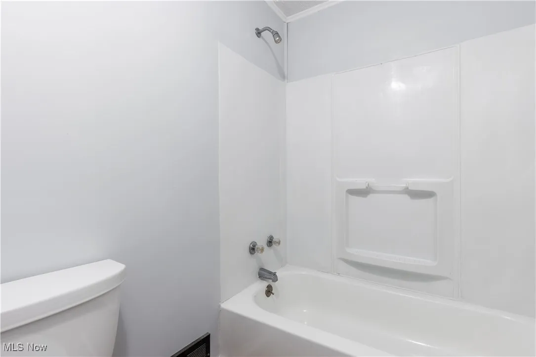 Bathroom with toilet,  shower combination, and ornamental molding