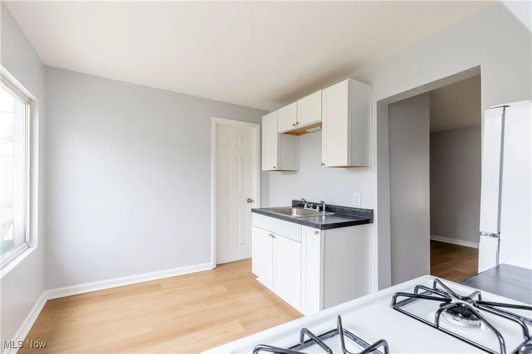 Kitchen featuring a sink, light wood finished floors, freestanding refrigerator, and baseboards